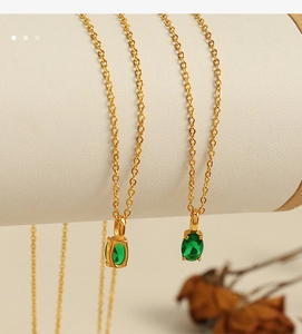 Close-up of gold chain necklace featuring an oval emerald green zircon pendant