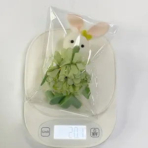 Close-up of Easter plush bunny with floral decor on scale weighing 20.1 grams