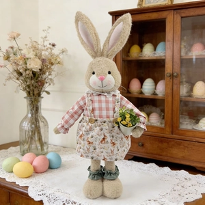 Detail of plush Easter bunny figurine with floral dress and small potted yellow flowers