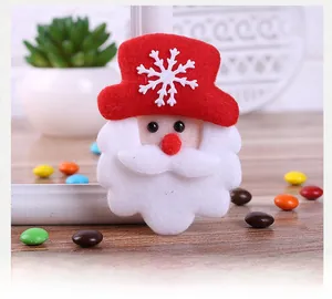Detailed view of handmade felt Santa Claus brooch with snowflake on wooden background