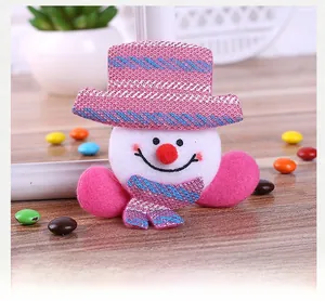 Close-up of pink and white plush snowman Christmas brooch on wooden table decor