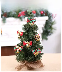 Nahaufnahme eines Mini-Weihnachtsbaums mit roten karierten Schleifen und goldenen Glocken