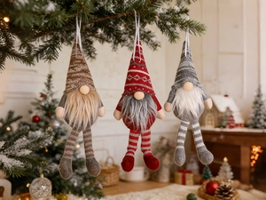 Three plush Christmas gnome hanging ornaments with striped legs on a snowy tree branch