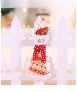 Détail d'un bonhomme de neige en tissu avec jupe à carreaux et écharpe rouge sur un sapin