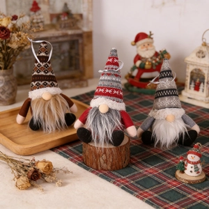 Three plush Christmas gnomes with knit snowflake hats and long beards on wood decor