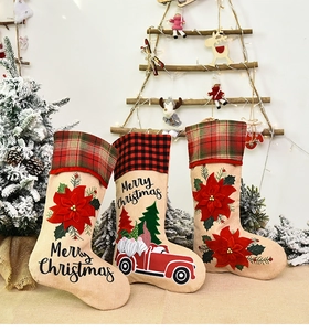 Three burlap Christmas stockings with gnome, truck, and floral embroidery detail on table