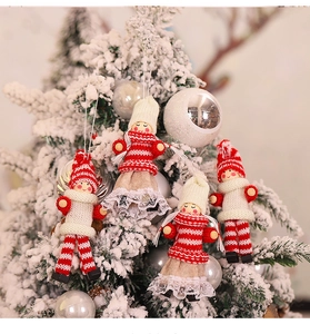 Close-up of four knitted Christmas faceless dolls hanging on a snowy Xmas tree branch