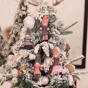 Handmade Christmas angel tree ornaments in pink and grey knit on snowy pine branches