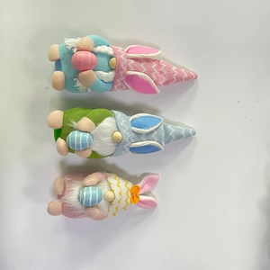 Detalle de tres gnomos de Pascua con orejas de conejo y huevos de colores a rayas