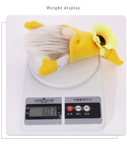 Display del peso di uno gnomo del raccolto con cappello di girasole su bilancia