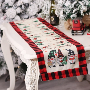 Christmas table runner with gnomes and red black plaid borders on a white table