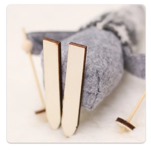Detailed macro view of laser-cut wooden skis on a gray felt holiday gnome decoration