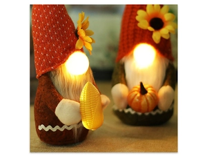 Close-up of glowing autumn gnomes with sunflowers holding decorative pumpkin and corn