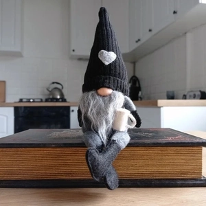 Nordischer Weihnachtsgnom Plüsch mit schwarzer Strickmütze auf alten Büchern
