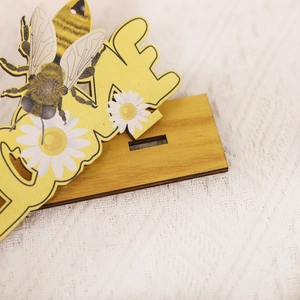 Rustic wooden bee and daisy flower table ornament with a dark wood grain base stand
