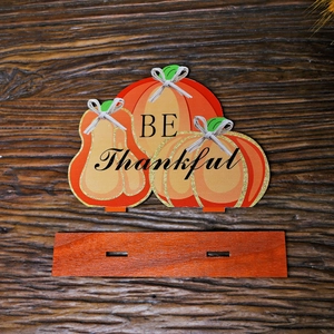 Three orange wooden Thanksgiving pumpkins with BE Thankful text on a rustic wood background