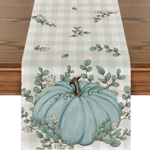 Detail of linen table runner featuring pumpkin and eucalyptus print on checkered fabric