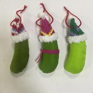 Three plush green Christmas pickles with festive knitted hats and red hanging strings