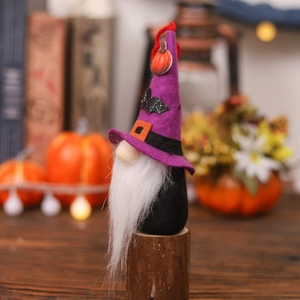 Halloween gnome plush with purple wizard hat, bat and pumpkin on a festive table