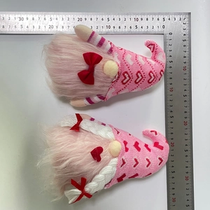 Detailed size measurement of pink knit Valentine gnome plushies using an L-shaped ruler