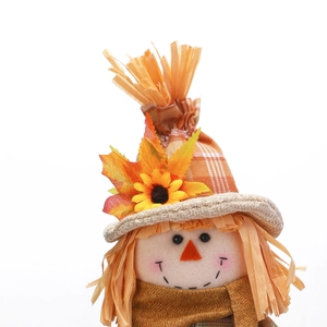 Close-up of scarecrow doll with sunflower hat and autumn maple leaf details