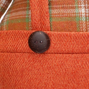 Detailed macro shot of harvest scarecrow doll featuring orange fabric and a wood button