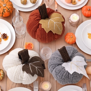 Three handcrafted knitted pumpkins with rustic stems for autumn harvest table decoration