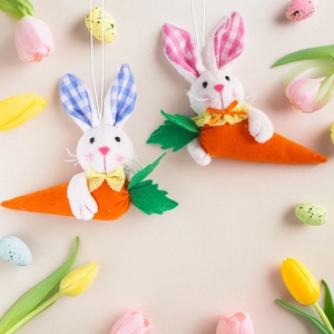 Pair of Easter plush rabbit pendants holding carrots with colorful egg and tulip background
