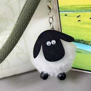 Cute plush sheep keychain hanging on a white bag with a silver metal chain
