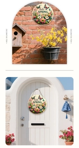 Detail of round Hello Spring wooden sign with flowers and butterflies on brick wall