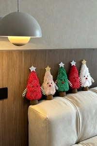 Group of cute plush Christmas tree ornaments with colorful fur and star tops on a sofa