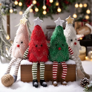 Lot de quatre poupées de Noël en peluche avec longues jambes posées sur une boîte en bois enneigée