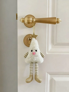 Close-up of plush Christmas tree doll hanging on a door handle for festive home decor