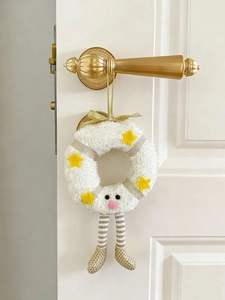 Close-up of plush Christmas wreath pendant with cute cartoon face on a door handle