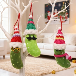 Close-up of three handmade green pickle ornaments with colorful knit hats and scarves