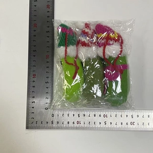 Three knit Christmas pickle ornaments with colorful hats and scarves, measured by a ruler