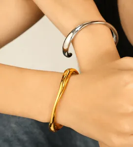 Close-up of wavy 18k gold and silver plated open bangles in a stacked minimalist style