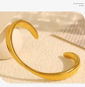 Macro shot of polished gold-plated open cuff bracelet with minimalist asymmetric design