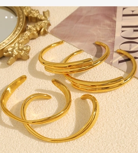 Set of four 18k gold plated open bangles with high polish finish on a neutral surface