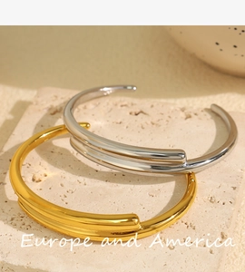 Close-up of dual-layer open metal bracelets in gold and silver finish on stone