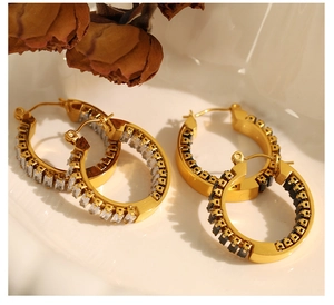 Nahaufnahme von Vintage-Ohrringen mit Zirkonia-Steinen in einer Keramikschale auf Goldbasis
