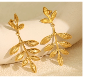 Detail of gold leaf drop earrings featuring intricate leaf veins and a polished finish