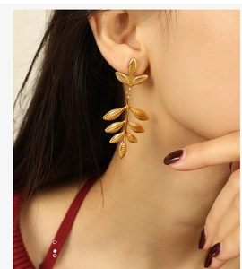 Close-up of elegant gold leaf drop earrings with natural texture on female model