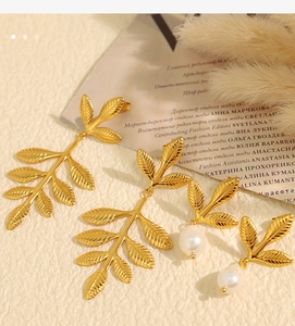 Close-up of golden leaf earrings with pearl detail and delicate embossed vein textures