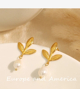Macro detail of vintage gold leaf earrings with teardrop pearls and textured metal leaf veins