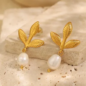 Vintage golden leaf pearl hoop earrings displayed on a natural stone background