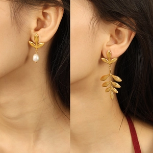 Golden leaf earrings with white pearl detail and brushed matte finish on female model
