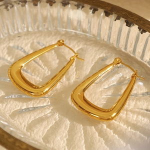 Minimalist 18k gold plated U-shaped geometric earrings on a vintage glass tray
