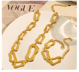 Dettaglio del set collana e bracciale a catena grossa dorata su rivista di moda