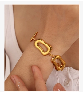 Dettaglio del bracciale a catena dorata con maglie irregolari e chiusura a T